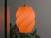 Eye-catching orange ceiling lamp shade with a spiral pleated design, creating a warm and inviting glow.