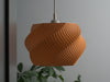 Unique orange ceiling light shade featuring a sculptural wave texture, enhancing room ambiance.